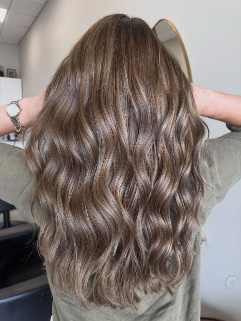 Long, glossy neutral brunette waves with soft, blended dimension, back view — hair by Alchemy Loft