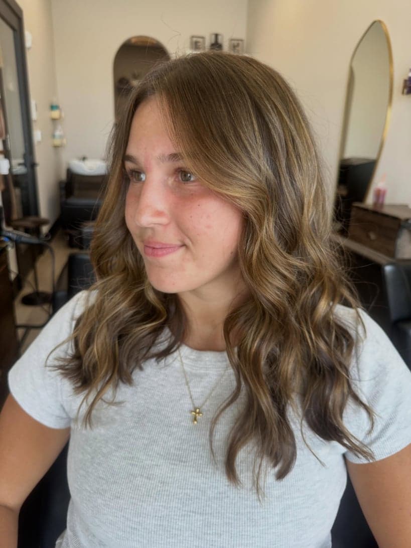 Brunette with warm caramel brightness around the face and soft painted pieces, front view — hair by Alchemy Loft